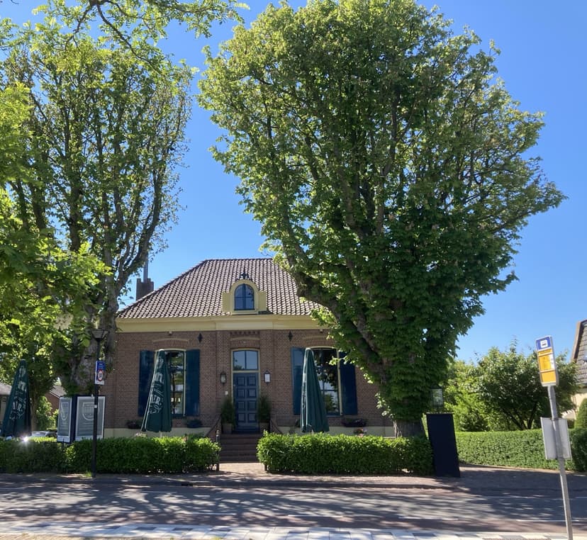 Het Oude Raadhuis aan de Wakkerendijk, nu een restaurant, tussen hoge bomen