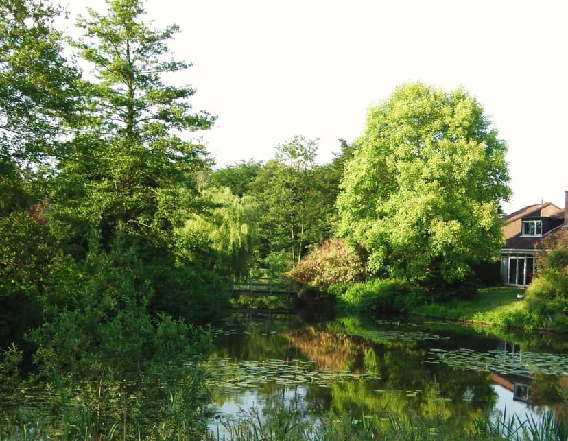 Vijver met waterlelies en een woonhuis aan de rand van Park Wildenburg in Leusden