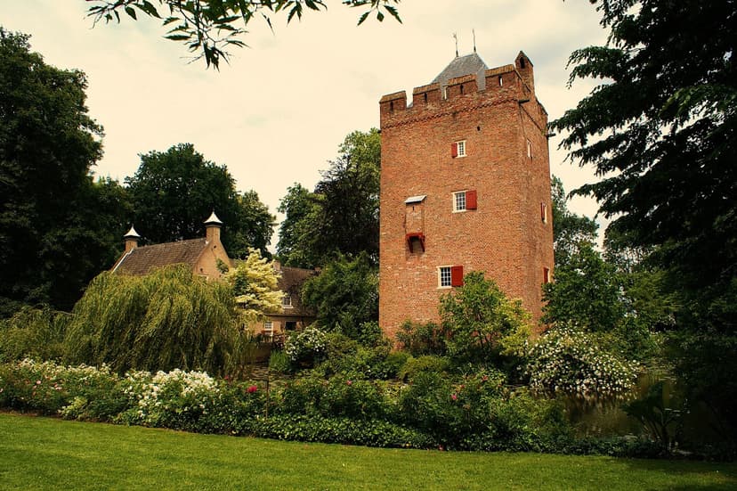 De toren van Kasteel Lunenburg tussen bloeiende struiken bij Langbroek