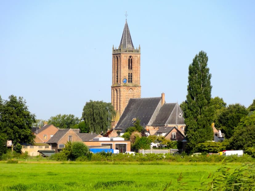 De toren van de Grote of Sint-Nicolaaskerk boven de daken van Eemnes, gezien vanuit de weilanden