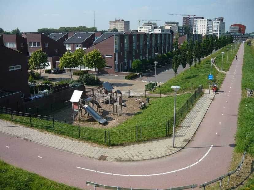 Rijtjeshuizen en een speeltuin in Waterstede, met de hoogbouw van het Bisonspoor erachter