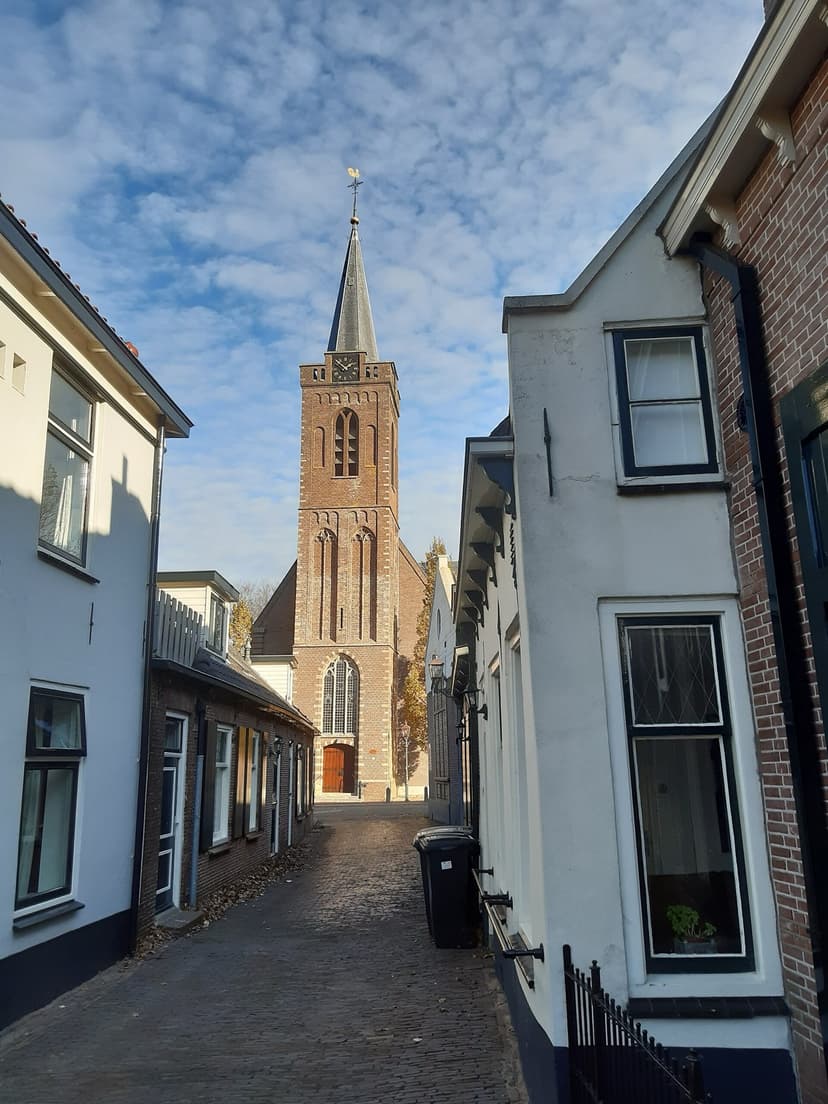 Steegje met witte huisjes en de toren van de Sint-Hippolytuskerk in Kamerik